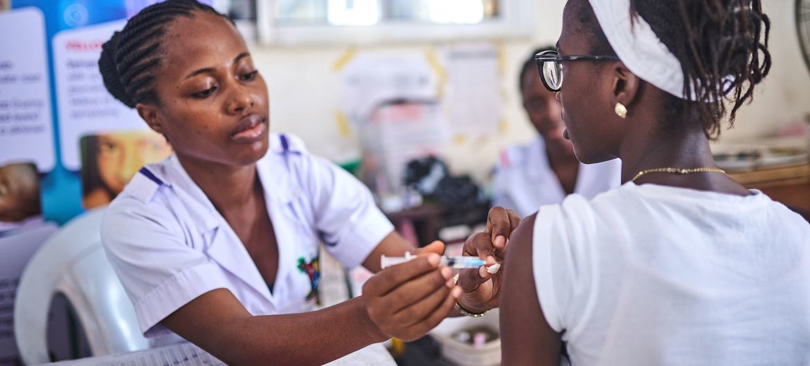 A female nurse administers a vaccine to a young girl at a clinic in Lagos, Nigeria.